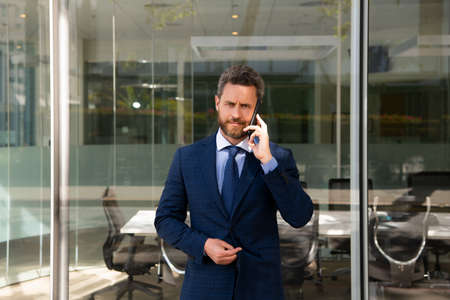 Handsome young businessman in suit talking on phone. Confident male manager.の写真素材