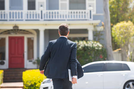 Back view of businessman going to work, carries a laptop in hand.の写真素材