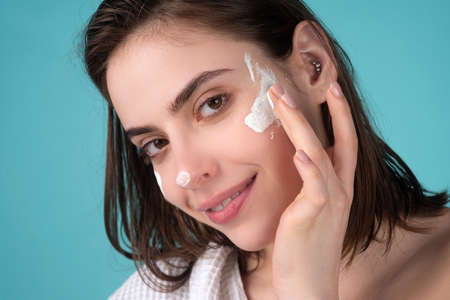 Beautiful woman, female skin care, close up face beauty closeup portrait. Girl apply facial cream lifting nourishing day creme on soft hydrated moisturized skin.の写真素材