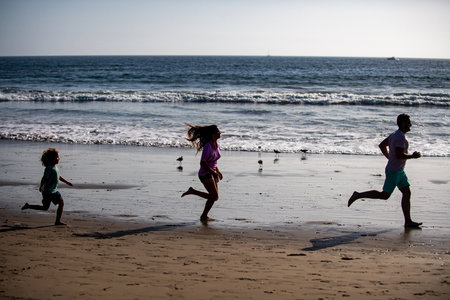 Silhouettes of family jogging along sea beach at sunrise. Outdoor workout, silhouettes of runners,...