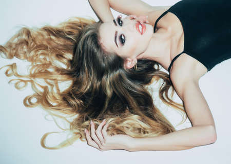 Hairdresser salon and hair care. Sexy girl with long curly hair in white studio.