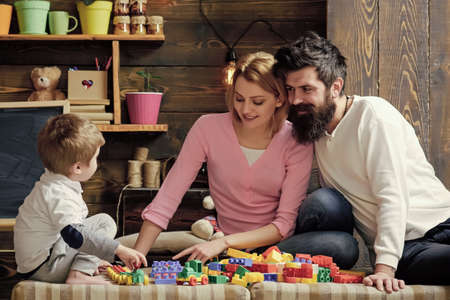 Happy family. Kids playing with toys. Father, mother and cute son play with constructor bricks....