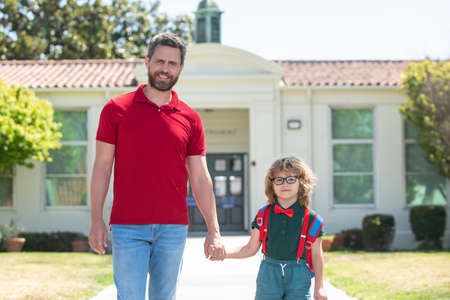 American father and son walking trough school park.の写真素材