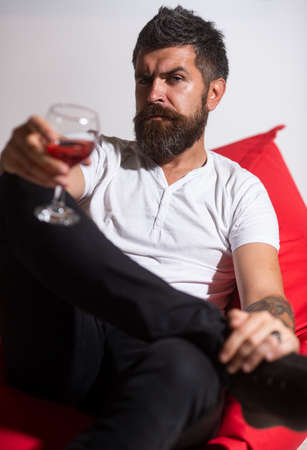 Depressed man drinking alone. Alcohol addiction. Bearded man with glass of wine. Alcohol dependence.の写真素材