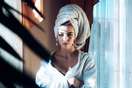 Beauty woman with towel on head relaxing, after spa or morning shower. Woman in bathrobe after wellness and skin care procedures. Rest, wellness and and care concept.の写真素材