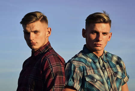Portrait of twin men brothers on blue sky