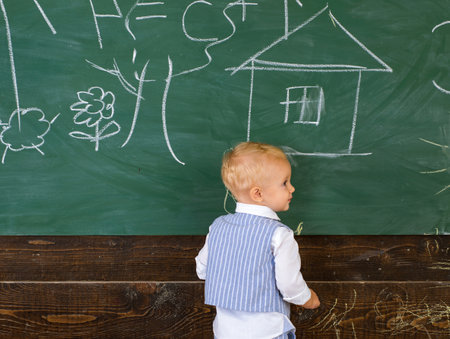 Pupil kid painting doodle on classroom chalkboard. Little artist boy creating picture on school day.