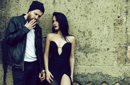 Urban couple. Pretty fashion woman and bearded man in stylish jacket and hat smoking cigarette. Bad habits, copy space.の写真素材