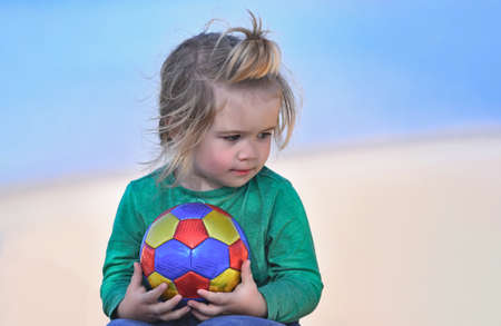Baby child boy holding ball at the coast of blue ocean outdoor, summer vacationの写真素材