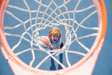 Amazed kid playing basketball holding ball with happy face.の写真素材