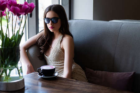 Enjoyng coffee in coffeeshop. Girl morning coffee break cappuccino americano latte espresso.