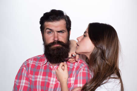 Barbershop procedures. Hairdresser concept. Woman hairdresser cuts beard with scissors. Man with long beard, mustache and stylish hair.の写真素材