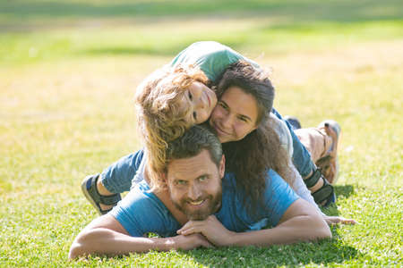 Happy young family hugging and embracing together outside in green nature.の写真素材