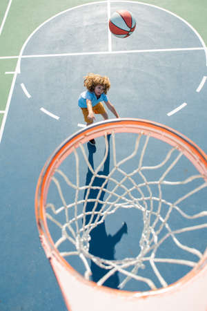 Child in basketball uniform jumping with basket ball for shot on basketball court.の写真素材