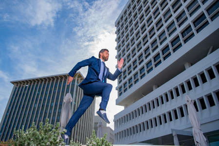 Business man running fast in a city street on urban background.の写真素材