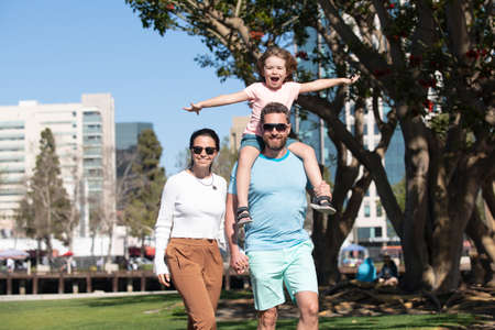 Parents with son walking in the city. Family taking a walk on street. Young couple walk in city park with son.の写真素材