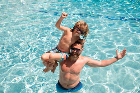Father and son on summer weekend. Child with dad playing in swimming pool. Pool party. Sport activity.の写真素材