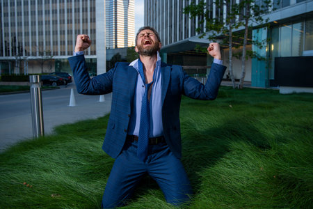 Business man crying in depression sitting on ground street suffering emotional pain, sadness, looking shocked and emotional furious.の写真素材