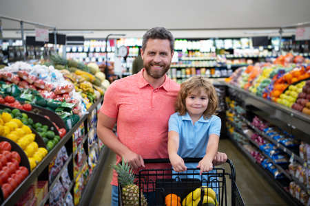 Father and son buy fresh vegetable in grocery store. Family in shop.の写真素材