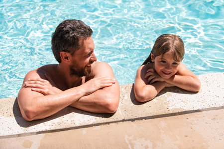 Dad and son having fun on summer vacation. Pool party. Family playing in swimming pool.の写真素材