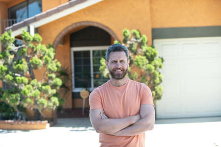 Happy young man. Portrait of handsome young man in casual t shirt keeping arms crossed and smiling while standing against new hame. Portrait of middle-aged man satisfied with life success.の写真素材