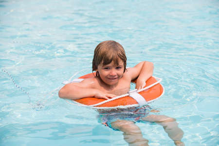 Child in summer pool. Happy kid on vacations at seaside. Kid swimming in pool. Summer holidays. Pool...