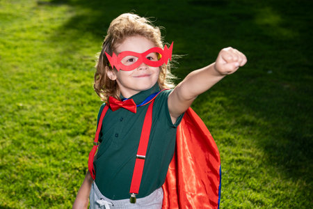 Superhero child against spring green field outdoor. Freedom and imagination kids concept.の写真素材