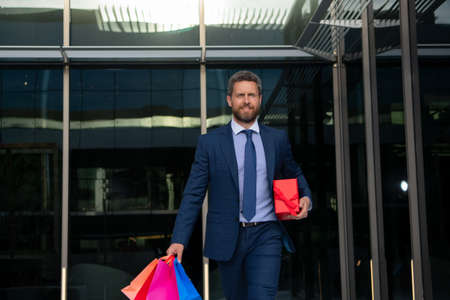 Business man doing shopping in the city. Portrait of businessman in suit with shopping bags.の写真素材