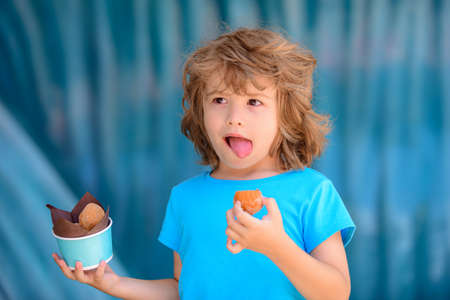 Kids lunch fastfood. Little boy child eating cookies outdoors in sunny summer day.の写真素材