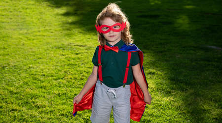 Hero Kid having fun outdoor. Superhero little boy on nature green background.の写真素材