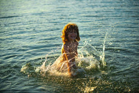 Boy kid playing on the beach on summer holidays. Child in nature with beautiful sunset sea. Happy...