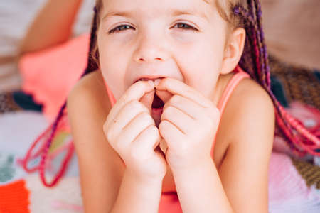 Kids teeth. Smiling girl holding missing tooth. Funny face close up.