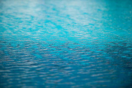 Blue pool water background. Blurred transparent clear calm water surface texture. Water waves in...