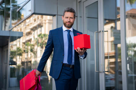 Great present. Man with gift box and smiling while standing against city.の写真素材