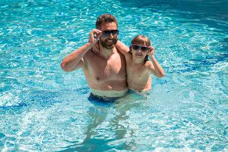 Father and son swimming in pool, summer family. Pool party. Family leisure. Summer vacation. Dad and son in pool.の写真素材