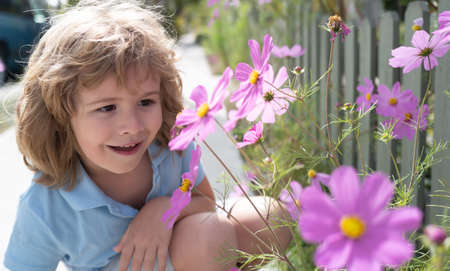 Funny child face close up. Kids head portrait with spring flowers outdoor.の写真素材