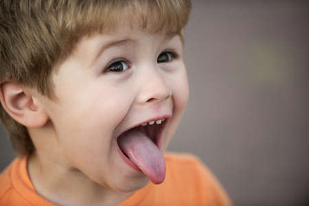 Kids funny face. Close up portrait of a cute little child show tongue. Childhood concept. Tongue out.の写真素材