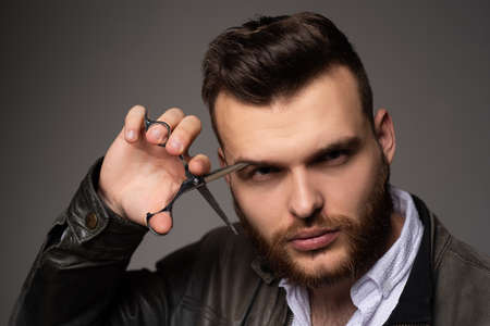Young sexy man, portrait of guy with barber scissors for barber shop. Modern barbershop, shaving. Handsome male with modern hairstyle on black.の写真素材