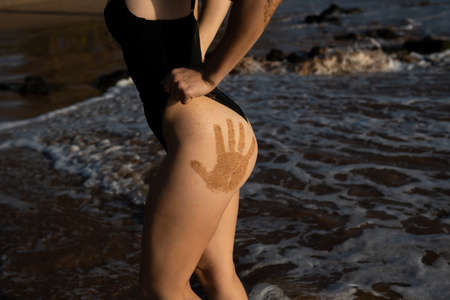 Closeup sexy butt with hand prints of woman in swimsuit at the barbados or virginia, beach. Women sensual body. Tanned booties of young model in bikini.の写真素材