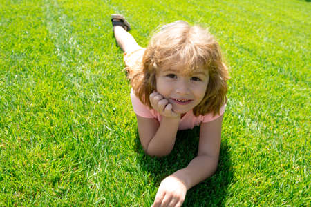 Portrait of little boy laying in grass. Children portrait.