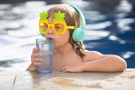 Close-up portrait of the cute boy swim and smiling in swimming pool. Drink water.