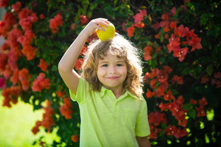 Little child with red apple on head outdoor.の写真素材