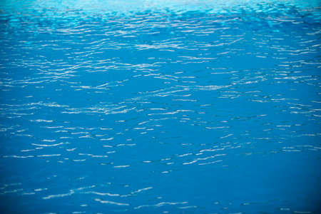 Ripple Water in swimming pool with sun reflection. Wavy water background.