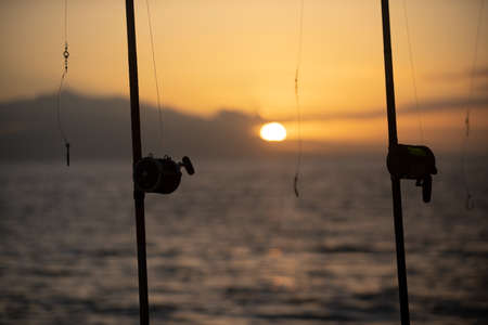 Fishing rods held in fishing rod holders. The rods are bent from the weight of the down riggers. Trolling for salmon of the coast.の写真素材