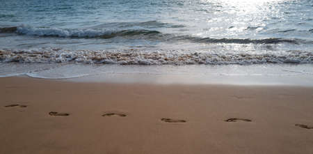 Beach, wave and footsteps. Summer vacation background.