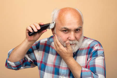 Middle aged bald man with hair clipper.の写真素材