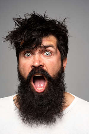 Man with beard and mustache, looks amazed and excited. Man haircut, modern hair style. Close up portrait of male model with long hair. Healthcare and hair care morning concept.の写真素材
