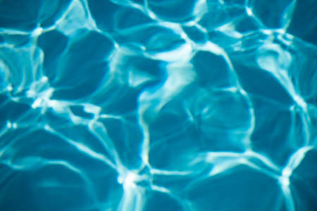 Background of blue water in swimming pool with sun reflection, ripple water wave in pool. Clear...