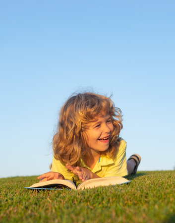 Kids imagination, innovation and inspiration children. Cute kid reading book outside on grass.の写真素材