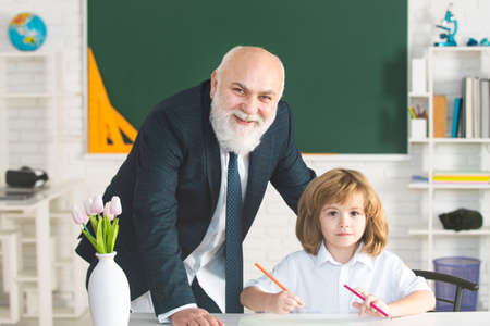 Professor or teacher teaching little student boy. Teacher is skilled leader. Educational conversation. Talking to students or pupils. School teacher concept. Pedagogue and pupil having fun.の写真素材